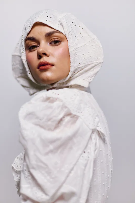 Portrait of a young woman in a white lace headscarf, embodying elegance and serenity, enhancing the concept of modest fashion and cultural identity