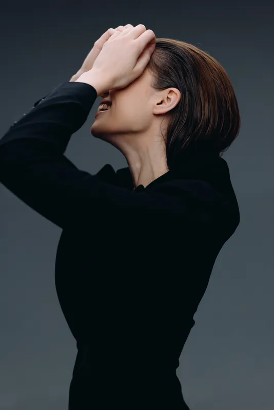 frustrated woman covering face with hand wearing black long sleeve top