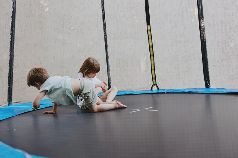Active children playing on a trampoline, enjoying fun and laughter while jumping together with excitement and curiosity in a playful environment.