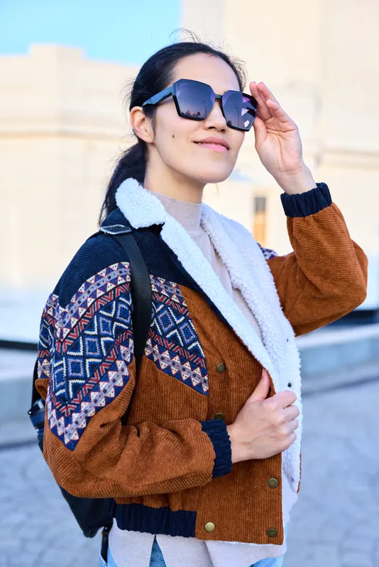 Fashion, streetwear, sunglasses, jacket, backpack, outdoor, urban, confident, style, casual, female posing under bright daylight, showcasing trendy outerwear and travel vibe for modern street style