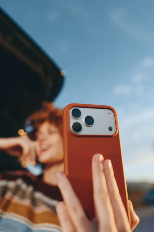 woman lifestyle smartphone mobile phonecase orange outdoors hand sky selfie, closeup view of orange smartphone in a hand, relaxed adult woman portrait blurred background, daylight sky