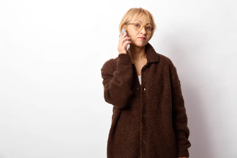 Woman elderly glasses coat worried thinking stress portrait hand white background, she touches cheek with fingers, anxious expression, concept for mental health stress, fatigue