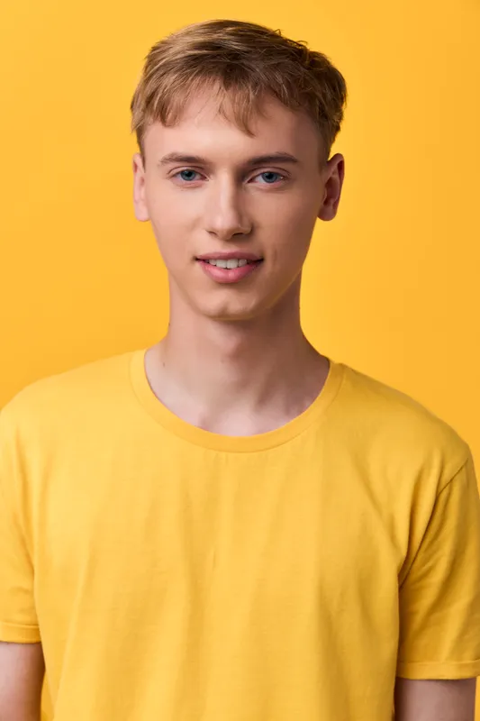 Young man in a yellow shirt with a friendly smile, studio lighting, front pose against a neutral background, casual fashion vibe suitable for lifestyle, ad, or product showcase