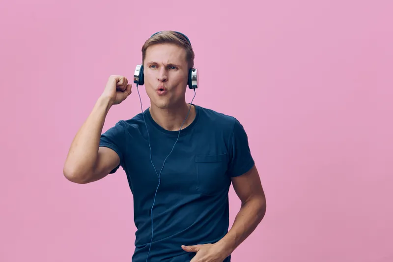 excited young caucasian man wearing headphones listening to music show fist punch isolated on pink background digital detox concept lifestyle