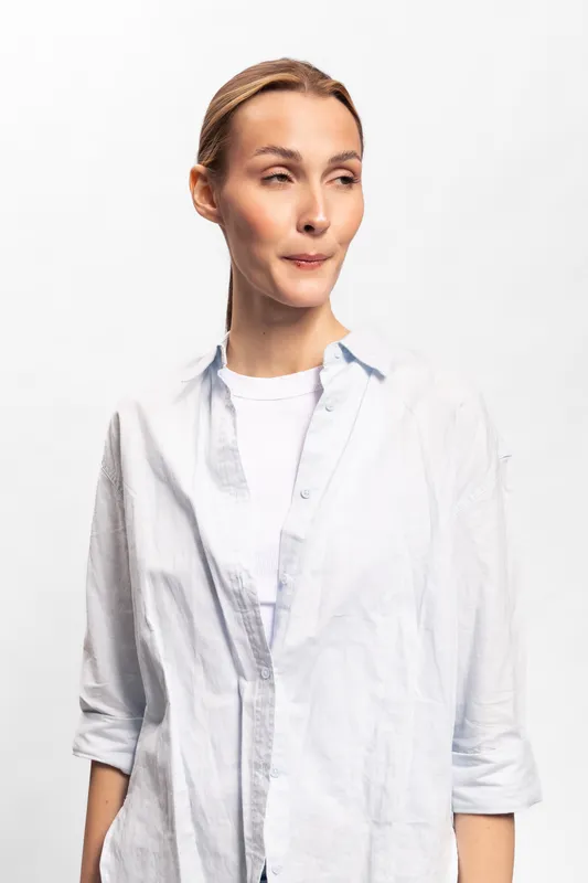 Woman in white shirt looks sideways with raised eyebrows and pursed lips. Portrait on white background. Concept for doubt, suspicion, and hesitation in communication.