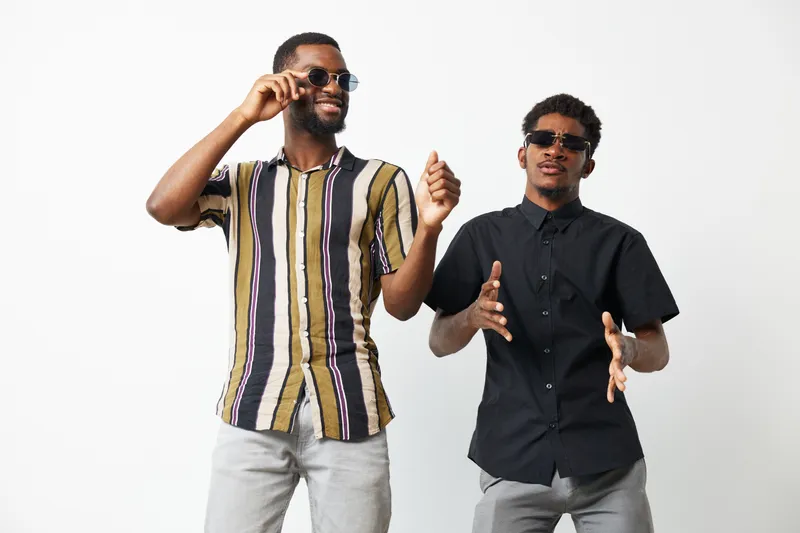 Joyful black men dressed in stylish shirts, enjoying their time together with sunglasses. Perfect for themes of friendship and celebration, capturing a lively moment.