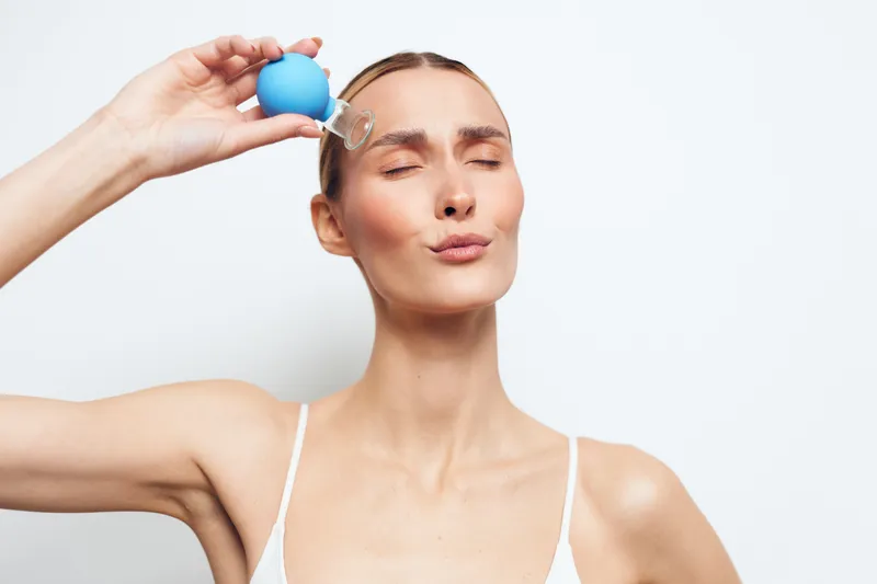 A serene woman applies a skincare product in a bright studio, eyes closed, calm expression, a moment of self care and wellness for skincare, beauty, and relaxation in a close up portrait