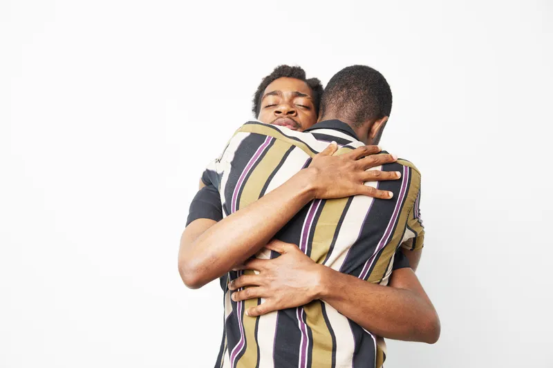 Two African American men sharing a warm and heartfelt embrace. The joy of friendship is captured in this colorful and expressive moment, showcasing connection.