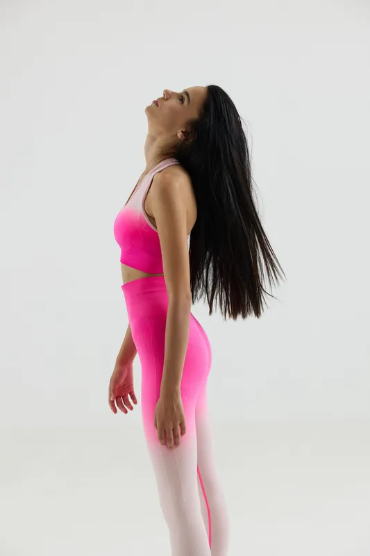 Young woman sport fitness wearing bright pink activewear, stretching and relaxing with long dark hair, isolated on white background, wellness and exercise concept.