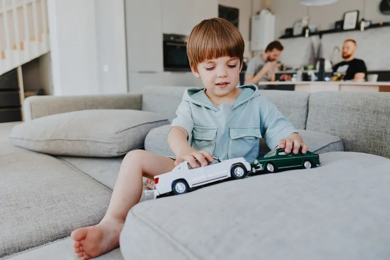 Playful boy enjoying toy cars in a bright living room, showcasing creativity and joy while engaged in imaginative play with his vehicles.