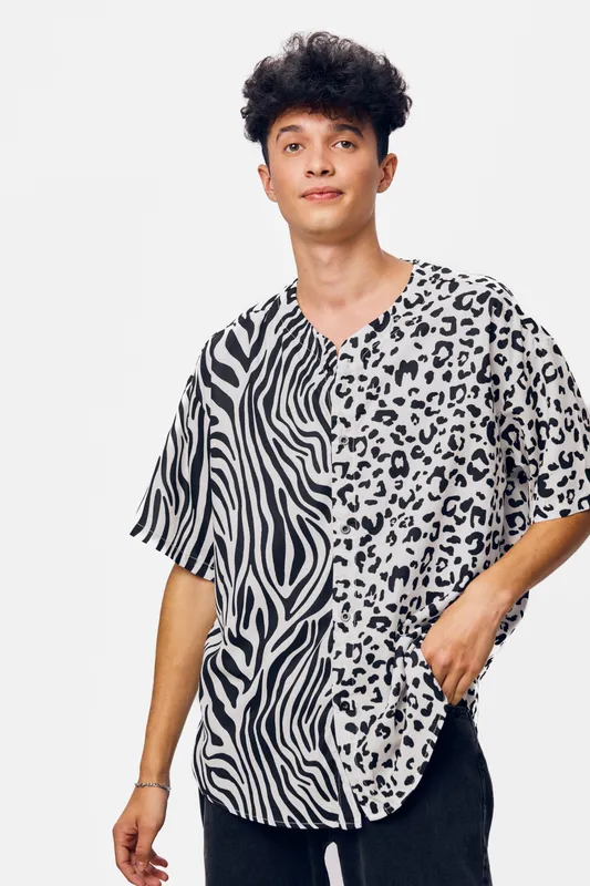 Young man wearing a black and white animal print shirt with mixed zebra and leopard patterns, standing against a plain white background, casual style, confident expression.