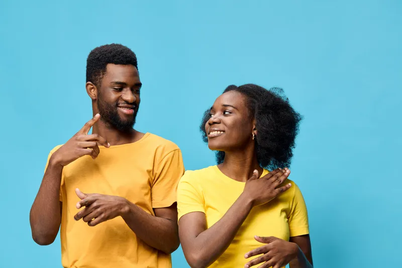 Cheerful couple in matching yellow t shirts against a bright blue background, expressing joy and connection, perfect for lifestyle and relationship themes