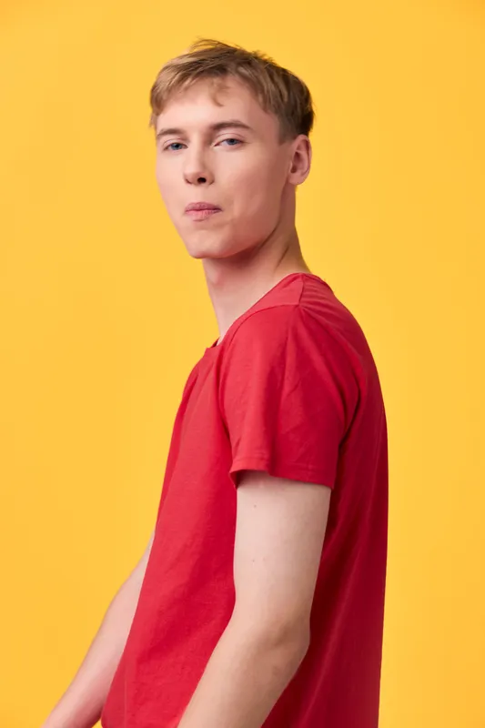 Young adult male in a red t shirt against a bright yellow backdrop, casual fashion shot highlighting bold color contrast and confident stance for lifestyle use