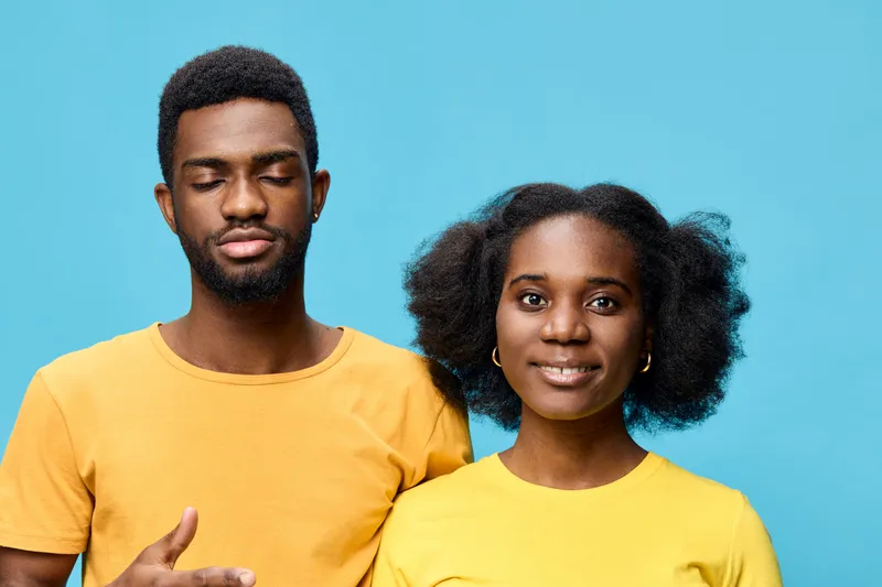 Happy diverse couple wearing yellow shirts against a blue background, showcasing joy and connection, ideal for concepts related to love and relationships