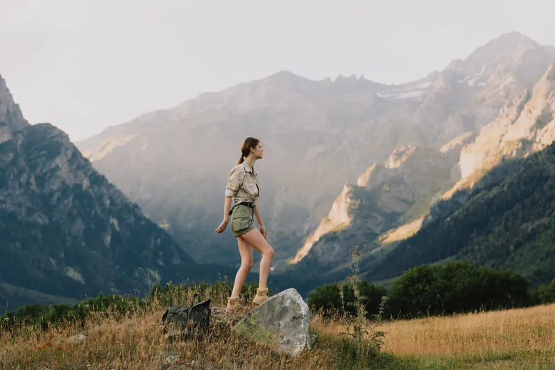 Young woman in casual clothes hiking on a rock in a mountain valley during daytime. Concept of outdoor lifestyle, adventure, and nature exploration.