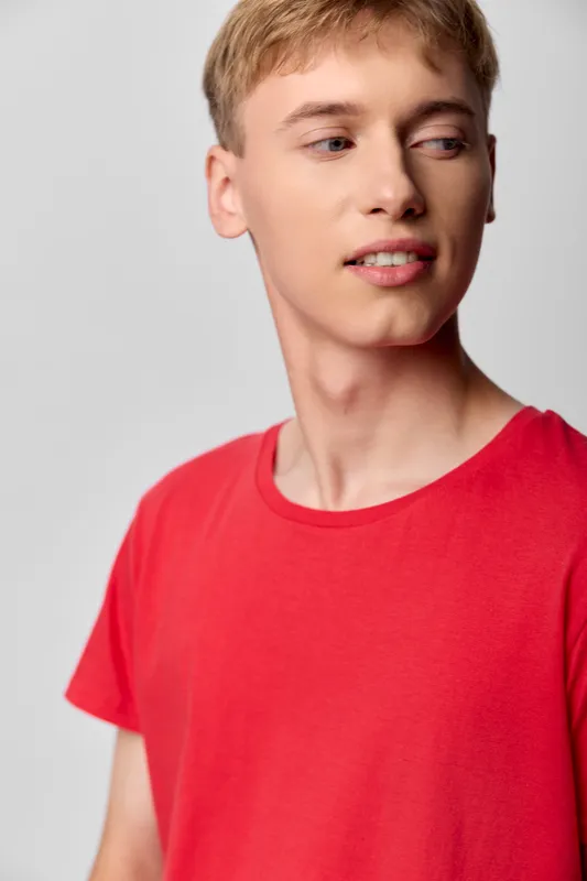 Young man in a red shirt looks away in casual style, conveying modern fashion and relaxed mood for lifestyle, apparel and media usage for marketing campaigns online
