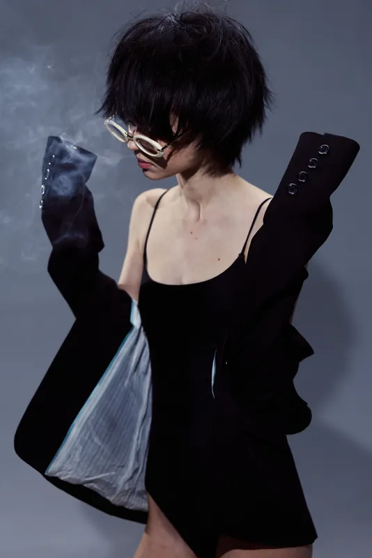 woman wearing black sunglasses and jacket with short hair in moody lighting