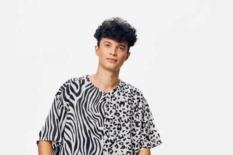 young man wearing a stylish black and white animal print t-shirt, standing against a plain white background, casual and modern fashion look