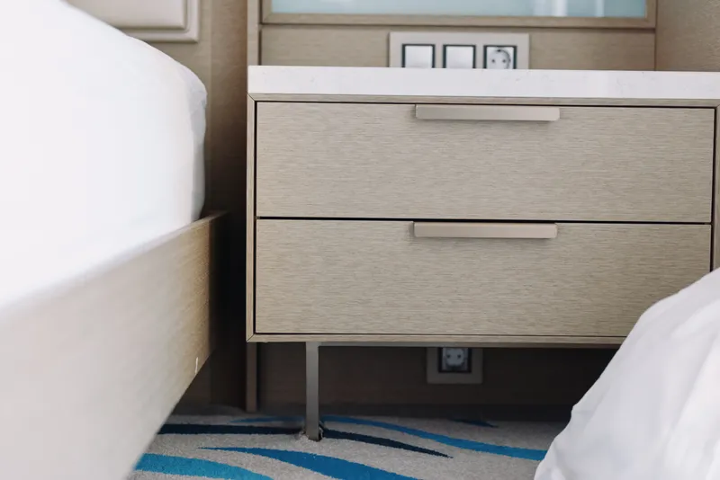 Two twin beds flank a wooden nightstand in a modern bedroom setup with neutral tones, clean lines and soft lighting for a calm hotel style space.