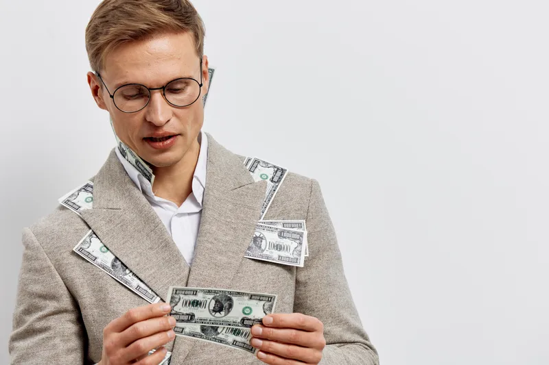 young caucasian man holding us dollar banknotes in beige jacket with money cash finance concept digital nomad remote work isolated white background