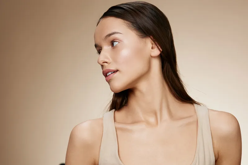 Elegant profile portrait of a young woman with smooth skin and long hair, showcasing beauty and confidence against a soft neutral background