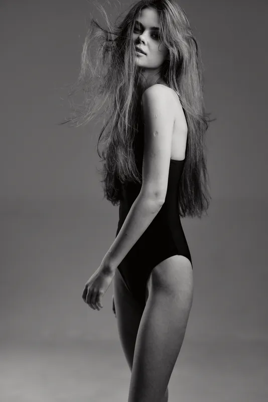 Black and white portrait of a young woman in a swimsuit with long hair and serious expression