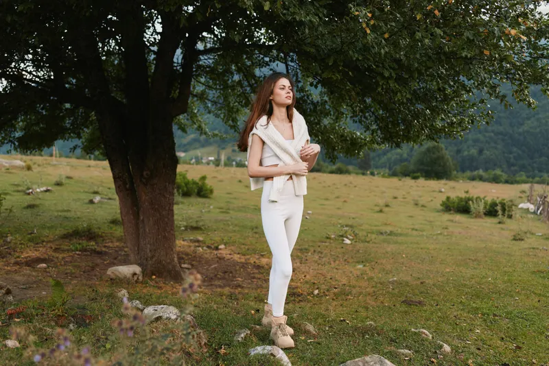 woman lifestyle outdoors field nature scenery serenity casual pose in sunlight among grass and tree, a candid model exudes calm in a natural rural setting