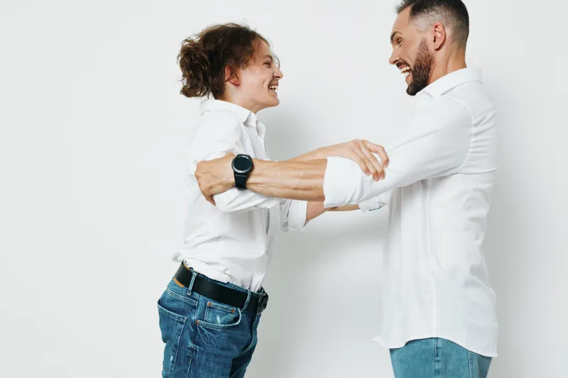 A business professional man shares a confident, joyful moment with a colleague, hands joined in a friendly handshake, highlighting emotion and teamwork against an isolated colored background.