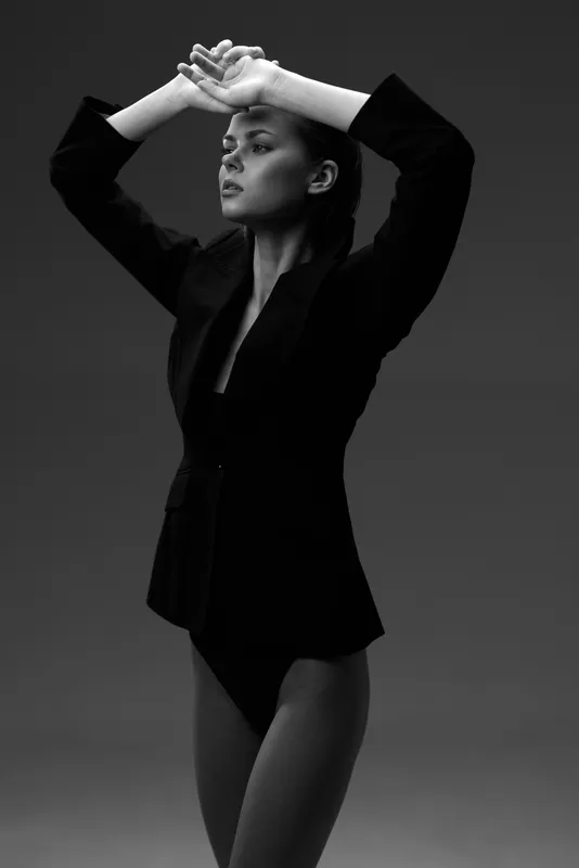 Black and white portrait of elegant woman posing in blazer with high contrast lighting and dramatic mood
