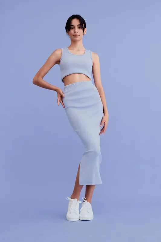 young woman posing in stylish blue ribbed two-piece outfit with white sneakers on pastel purple background, modern casual fashion, full-body portrait