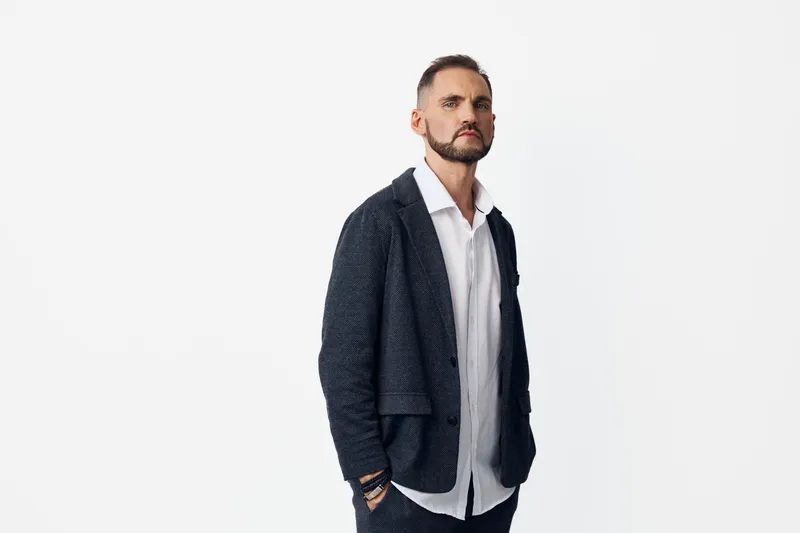 A confident professional man stands against an isolated colored backdrop, conveying calm focus, determination, and poised attitude in a smart suit.