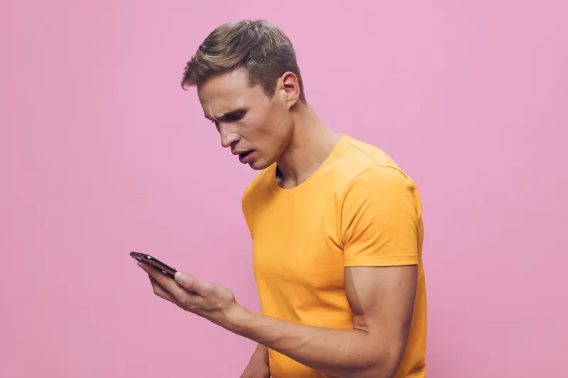 focused man using smartphone look screen wear yellow t-shirt isolated pink background digital detox concept technology communication