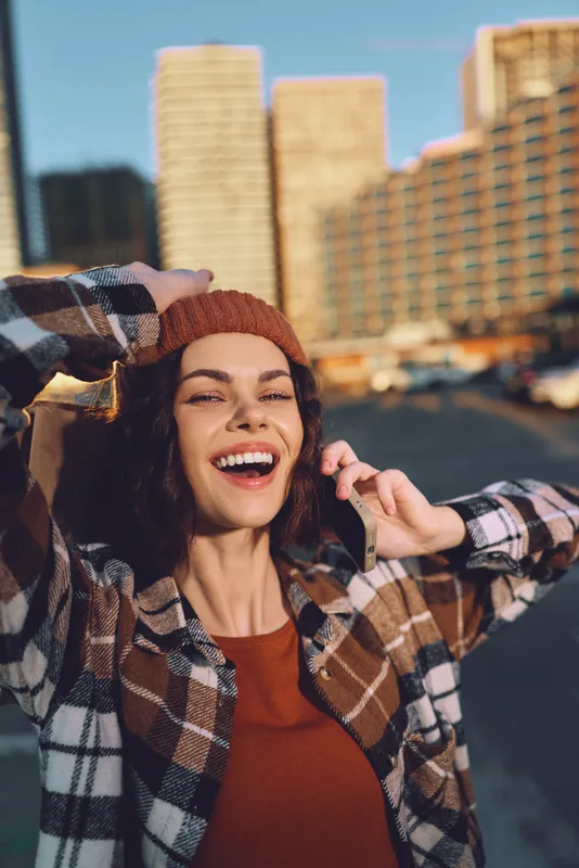 woman smile phone city beanie jacket sunlight candid portrait of a joyful woman on phone in urban golden hour glow, authenticity, mindful living and emotional storytelling