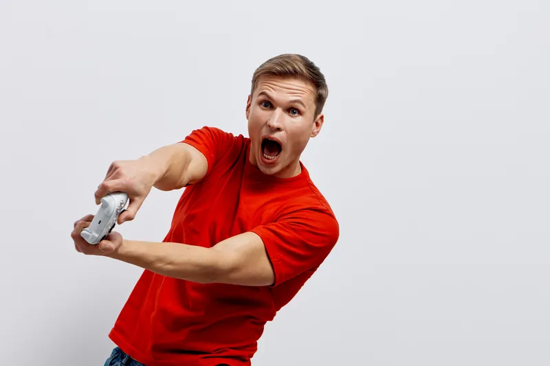 shocked young caucasian man wear red t-shirt holding game controller playing video games gaming digital entertainment concept