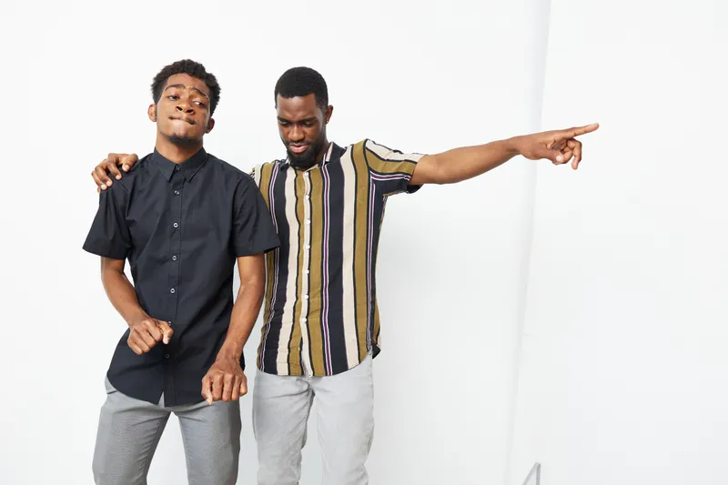Two black men enjoying themselves in a vibrant and colorful setting, showcasing happiness and camaraderie. A lively moment of friendship captured beautifully.