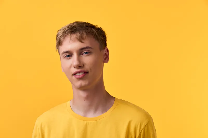Headshot of a smiling male in a yellow shirt against a bright yellow background, casual studio setup with clean composition for fashion, lifestyle and marketing use