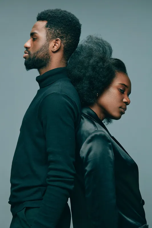 Elegant portrait of a couple with Afro hairstyle, showcasing emotional depth and style, with a monochromatic gray background, ideal for concepts of love and unity