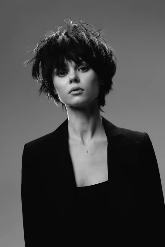 Black and white portrait of a serious young woman with short hair wearing a blazer, stylish and elegant mood.