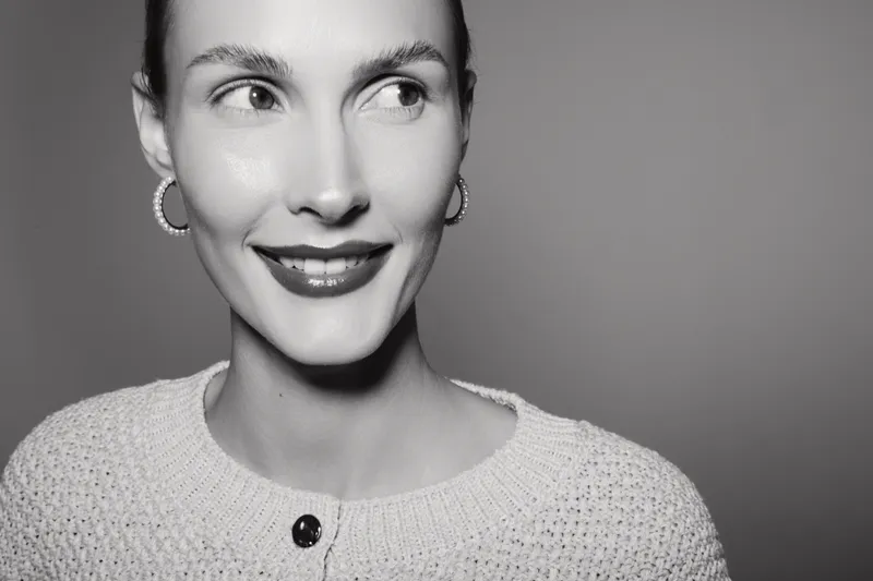 Smiling Caucasian woman with light skin and hoop earrings looks sideways in black and white portrait. Concept of happiness and beauty.