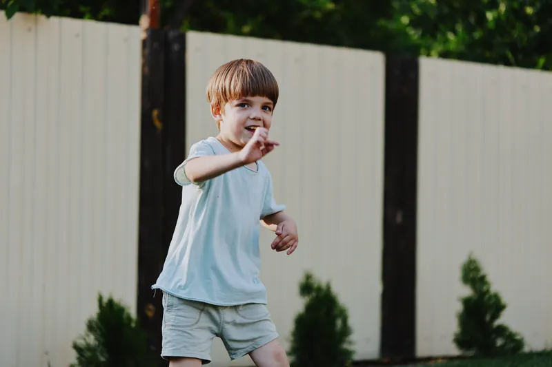 Happy boy playing outdoors, enjoying the summer sun with joy and excitement in a playful atmosphere surrounded by greenery. Perfect for family-oriented themes.