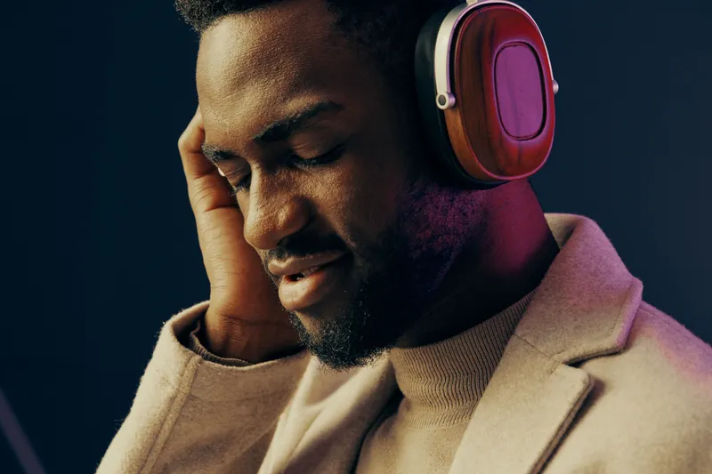 Happy young man with headphones enjoying music, dressed in a stylish outfit, against a colorful background, conveying relaxation and joy