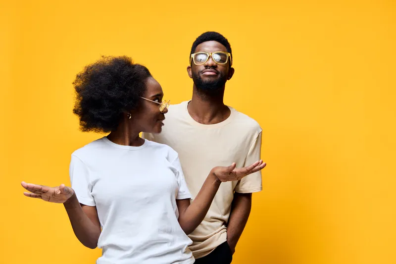 Stylish African couple in casual outfits expressing joy against a bright yellow background, perfect for lifestyle and fashion themes