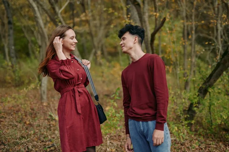 An intimate candid moment captures a natural connection between two people in a sunlit autumn park, conveying authenticity and credibility through relaxed posture, warm facial expressions, and