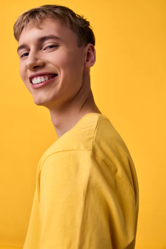 Smiling youth wearing a bright yellow shirt against a bold yellow backdrop, energetic and friendly for lifestyle, fashion, and positivity themes. Perfect for marketing, social media, and campaigns