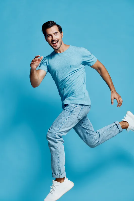 Full body smiling happy cheerful young man wear light blue t-shirt run look camera isolated on bright solid light blue background studio portrait. Active lifestyle concept