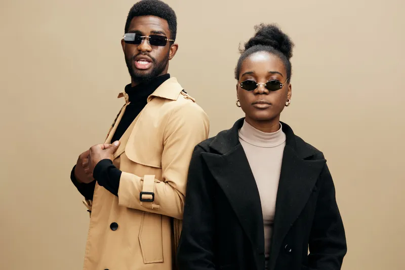 Stylish African models in fashionable outfits posing confidently against a neutral beige background showcasing contemporary fashion trends