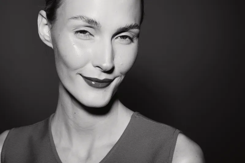 Close-up of a smiling caucasian woman with pale skin and slicked back hair on black background. Concept of beauty and confidence.