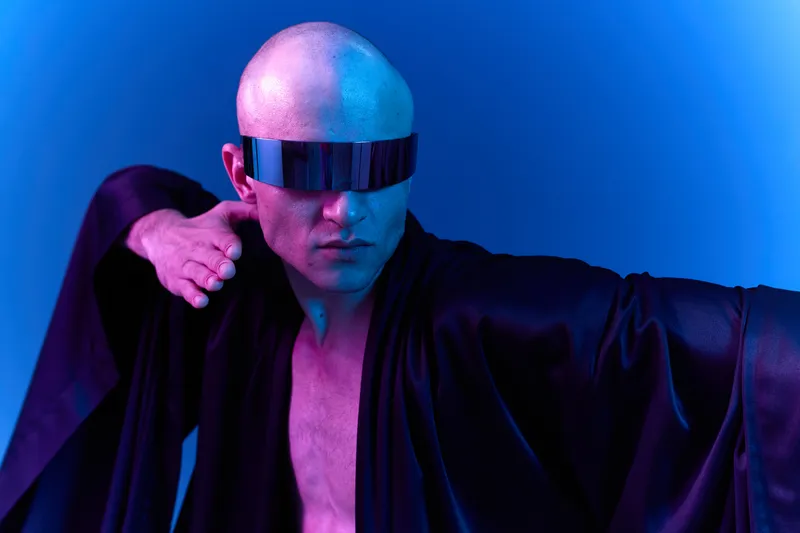 Futuristic man in stylish attire, showcasing confidence and strength, with dramatic lighting and sleek sunglasses illuminating a vibrant atmosphere.