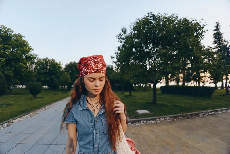 lifestyle woman in modern boho-western denim street style walking outdoors with natural greenery and film color effect capturing relaxed mood