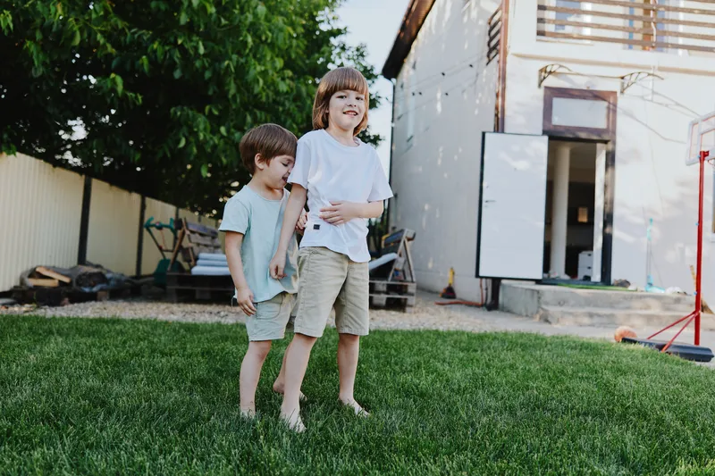 Happy children playing outdoors in a sunny backyard, enjoying their time together in the green grass, showcasing their playful spirit and innocence.